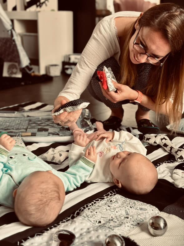 Eva accompagne des bébés pendant un atelier d’éveil en noir et blanc