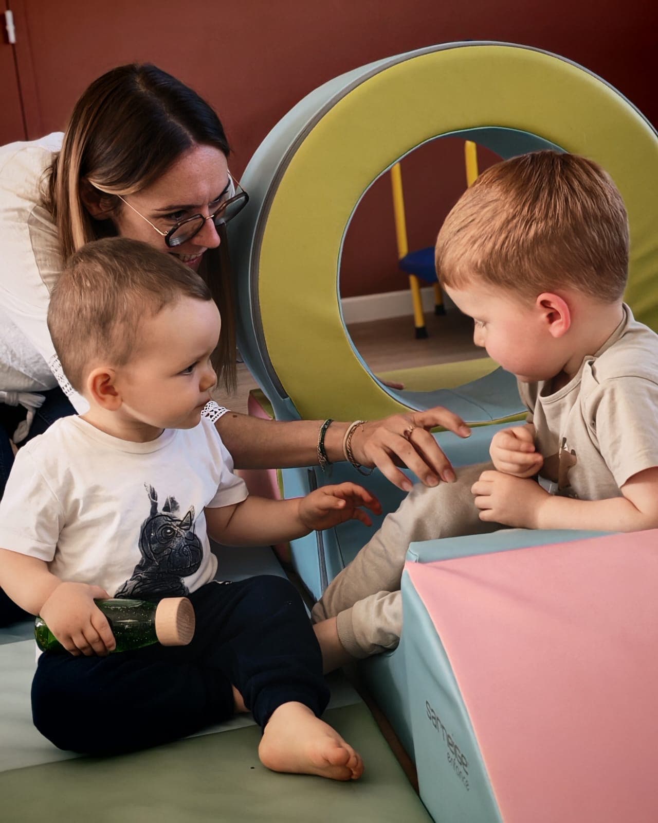 Eva accompagne deux enfants pendant un atelier de motricité